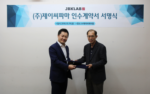 장봉근 제이비케이 대표(왼쪽)가 19일 제이씨파마 인수계약에 서명하고 진승하 제이씨파마 대표와 악수하고 있다.